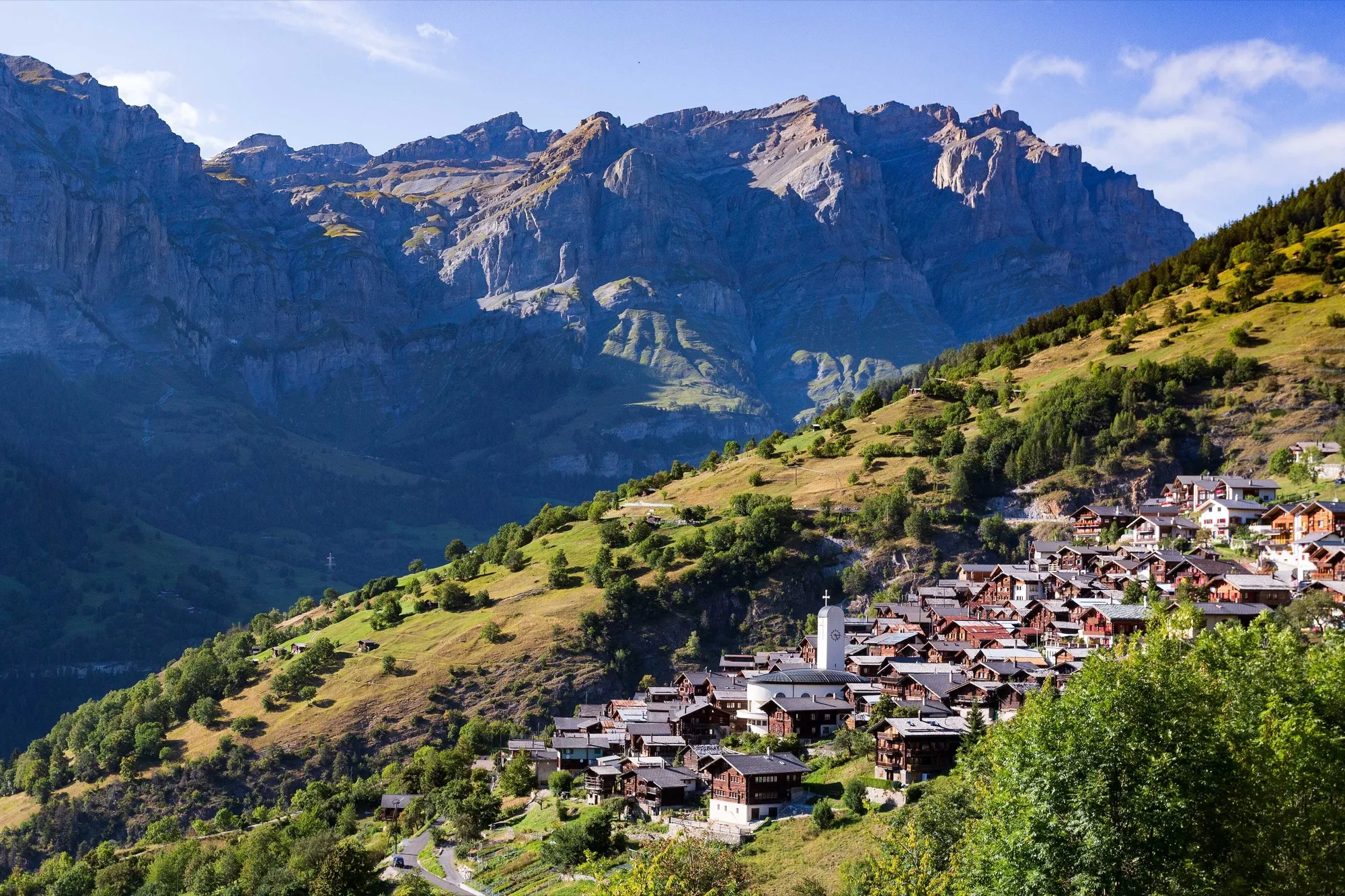 Das Bergdorf Albinen mit dunklen Holzhäusern am Hang, dahinter die Felswände über Leukerbad