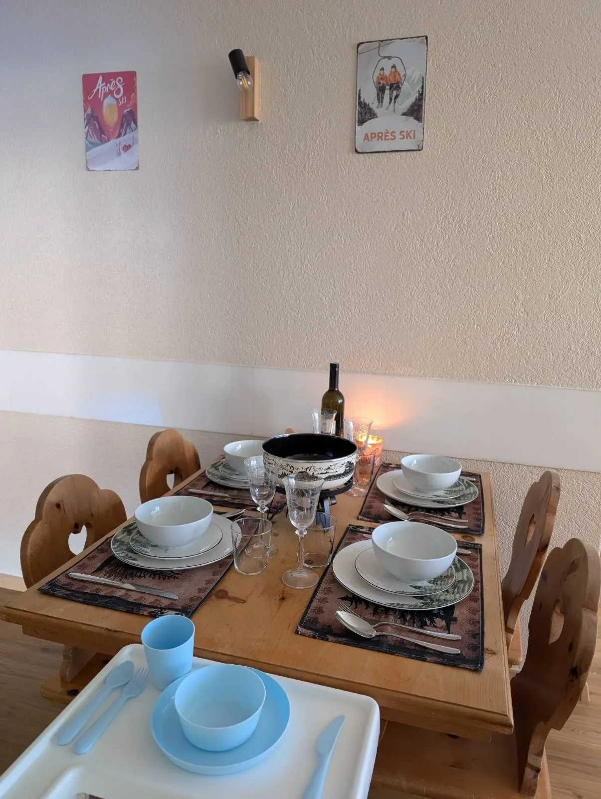 Esstisch mit Schalen, Weingläsern und einer Flasche, davor ein Hochstuhl