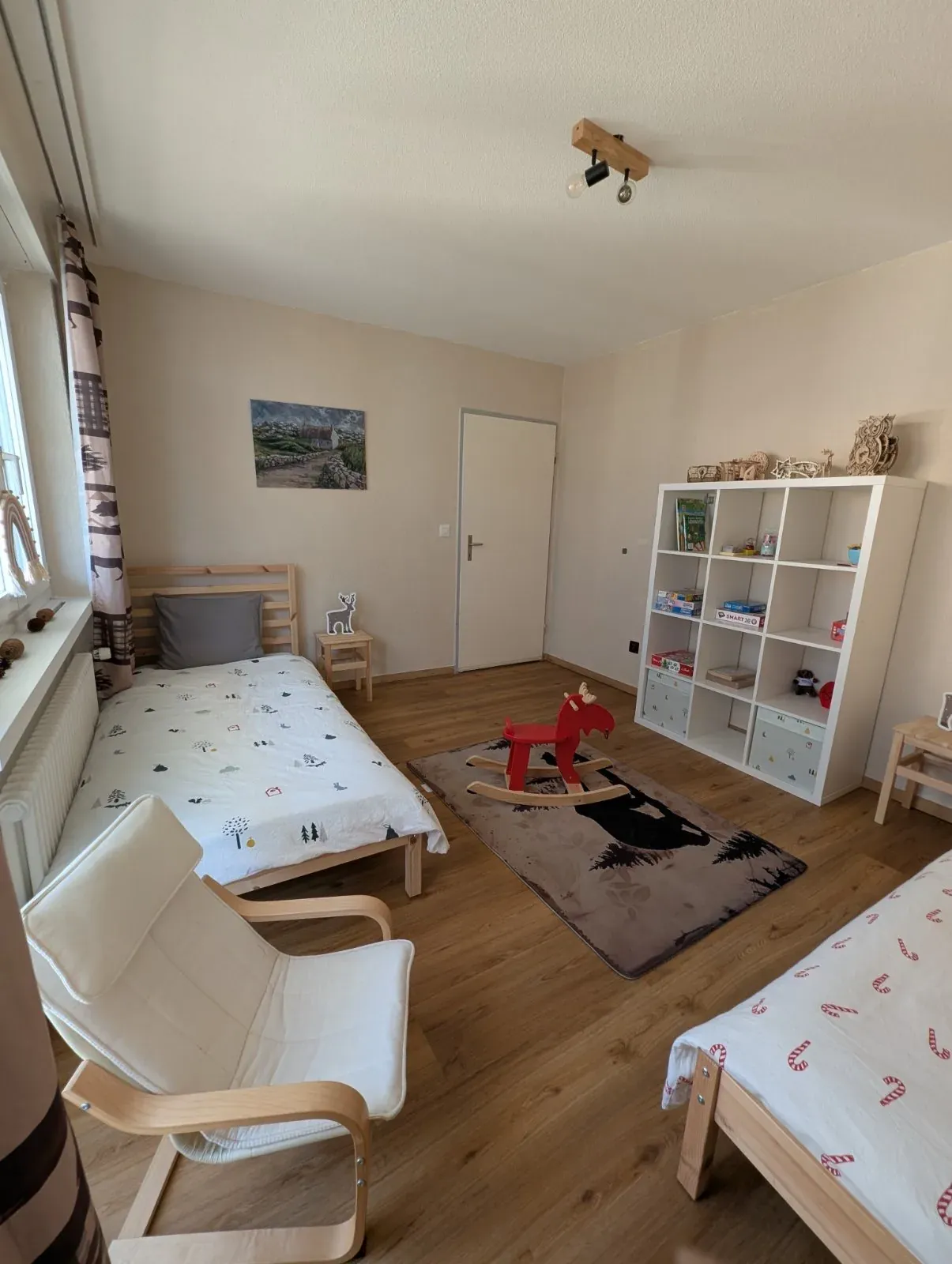 Kinderzimmer der Alpine Siesta mit zwei Betten, Regal und rotem Schaukeltier
