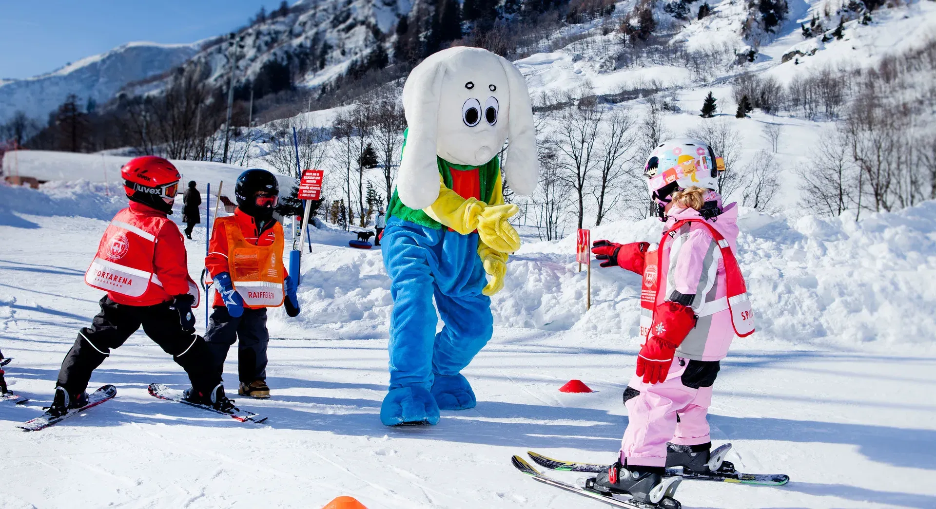 Grosses weisses Maskottchen zwischen Kindern mit Sportarena-Westen