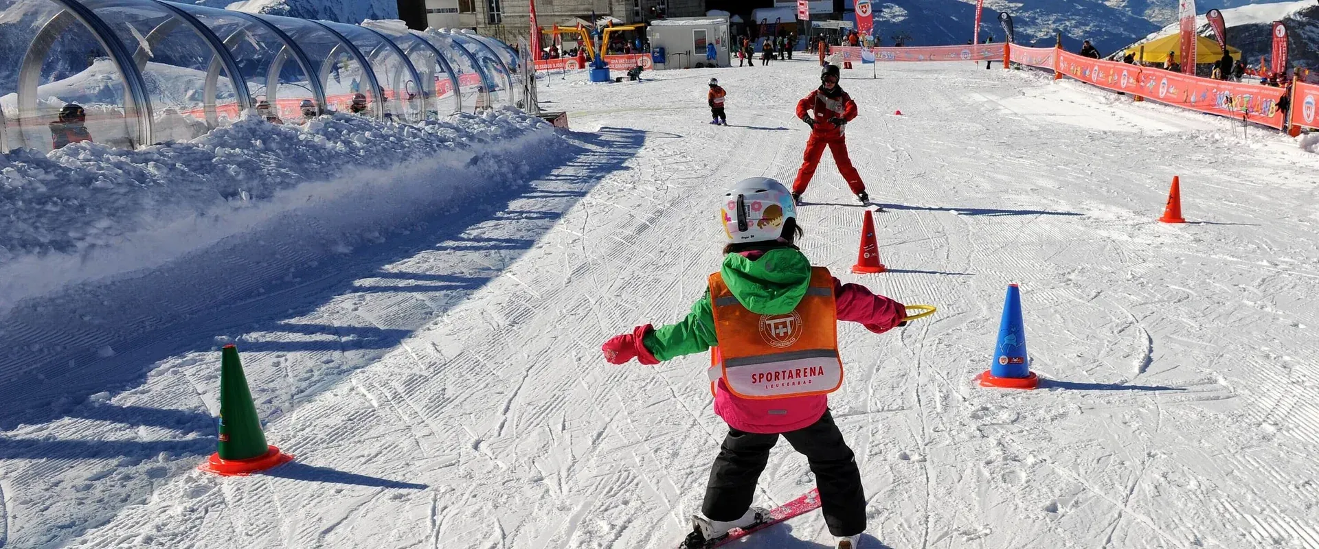 Kind von hinten mit oranger Weste Sportarena zwischen Pylonen
