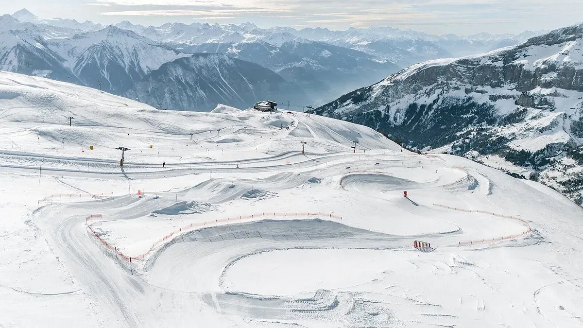Weite Piste mit markierten Kurven, Liften und einer Gipfelkette