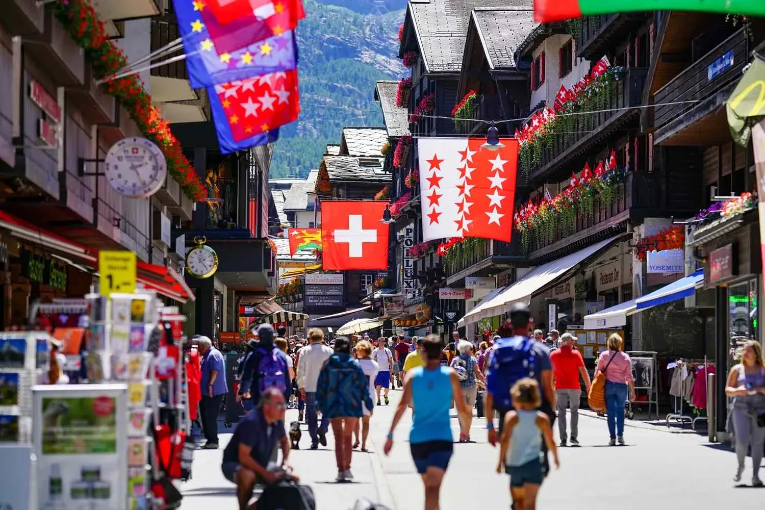 Volle Fussgängerstrasse mit Schweizer Fahnen und der Valais-Fahne